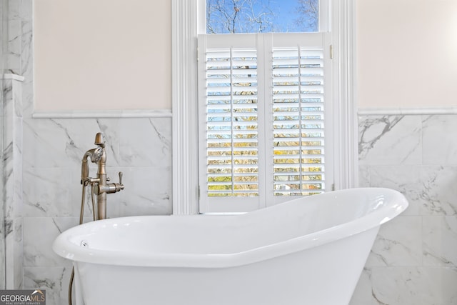 bathroom with a tub and tile walls