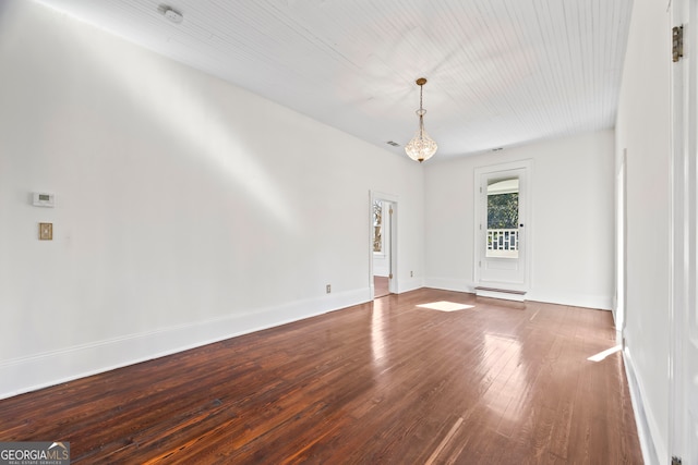 empty room featuring an inviting chandelier and hardwood / wood-style flooring