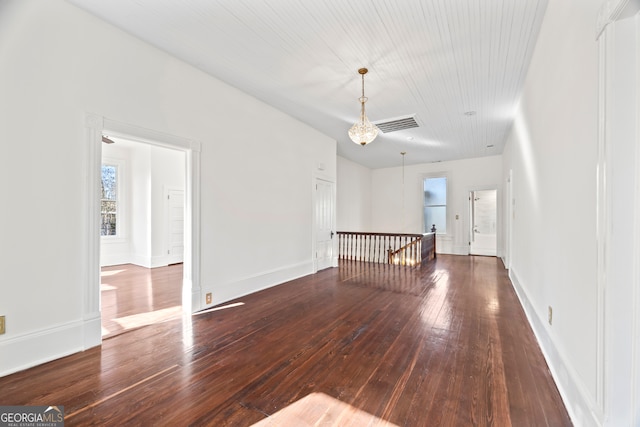 empty room featuring dark hardwood / wood-style flooring and a notable chandelier