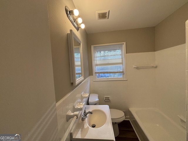 bathroom featuring tile walls, a bathing tub, toilet, and vanity