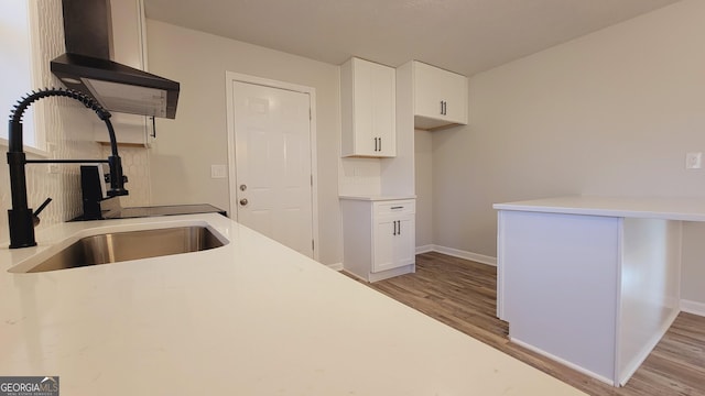 kitchen with white cabinetry, sink, extractor fan, and light wood-type flooring