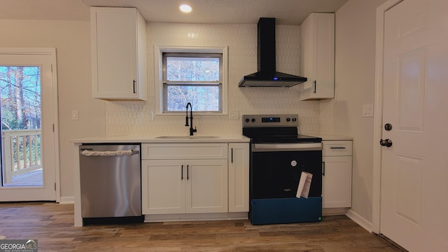 kitchen featuring white cabinetry, sink, wall chimney range hood, stainless steel dishwasher, and range with electric stovetop