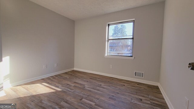 unfurnished room featuring dark wood-type flooring and a textured ceiling