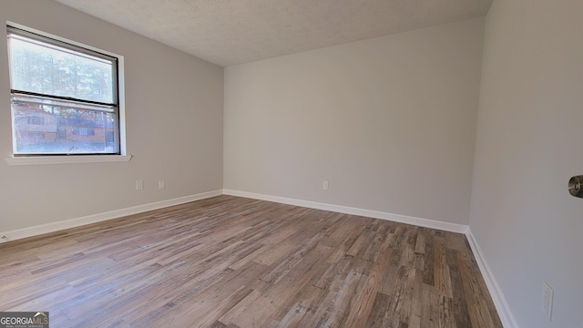 spare room with a textured ceiling and light hardwood / wood-style flooring