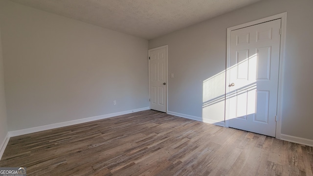 empty room with hardwood / wood-style floors and a textured ceiling