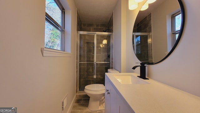 bathroom with tile patterned floors, vanity, toilet, and a shower with door