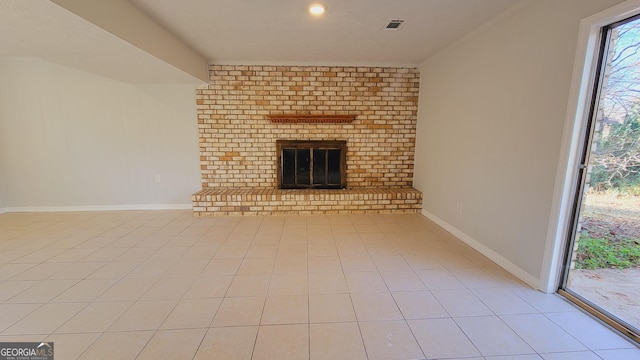 unfurnished living room featuring light tile patterned flooring and a brick fireplace