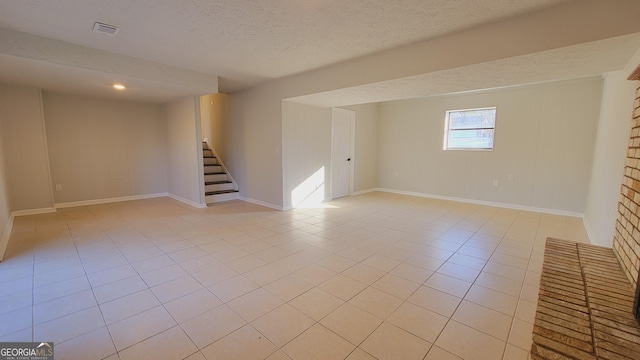 basement featuring light tile patterned floors and a textured ceiling