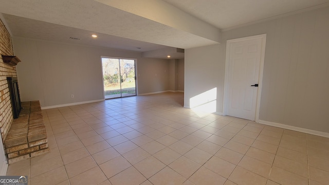 spare room featuring light tile patterned floors and a brick fireplace