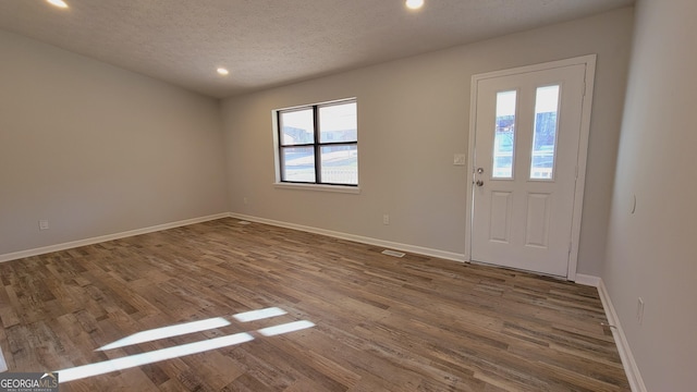 foyer entrance with plenty of natural light, dark hardwood / wood-style flooring, and a textured ceiling