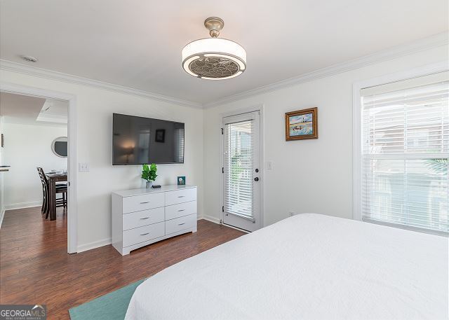 bedroom with access to outside, dark hardwood / wood-style floors, and ornamental molding