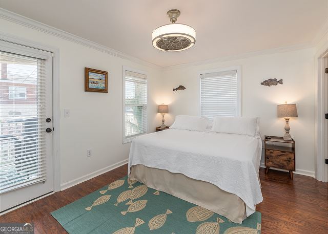 bedroom with dark hardwood / wood-style floors, access to exterior, ornamental molding, and multiple windows