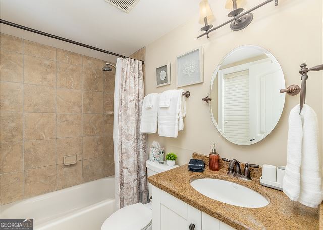 full bathroom featuring shower / bathtub combination with curtain, vanity, and toilet