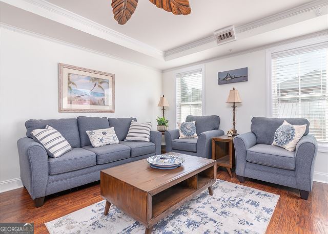 living room featuring ceiling fan, crown molding, and dark wood-type flooring