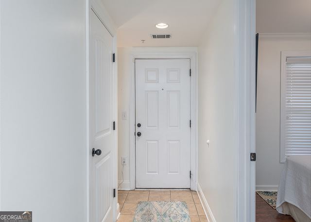 doorway to outside with light tile patterned floors and crown molding