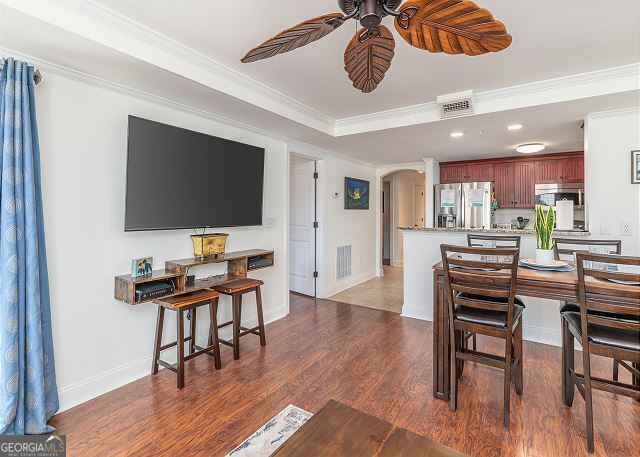 dining space featuring ceiling fan, ornamental molding, and dark wood-type flooring