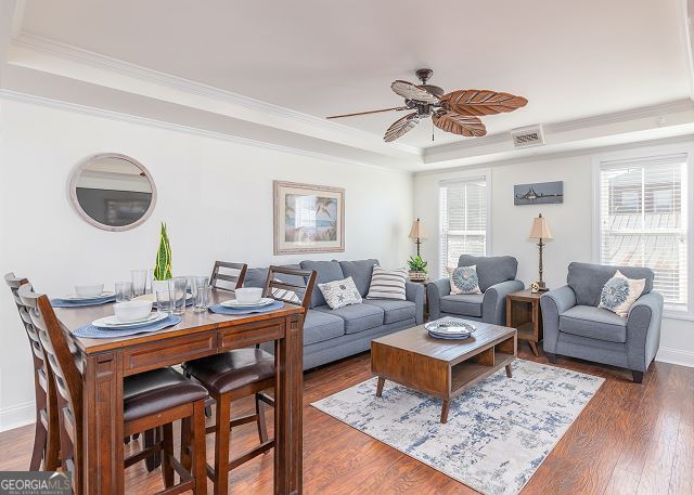 living room featuring ceiling fan, dark hardwood / wood-style floors, crown molding, and a tray ceiling