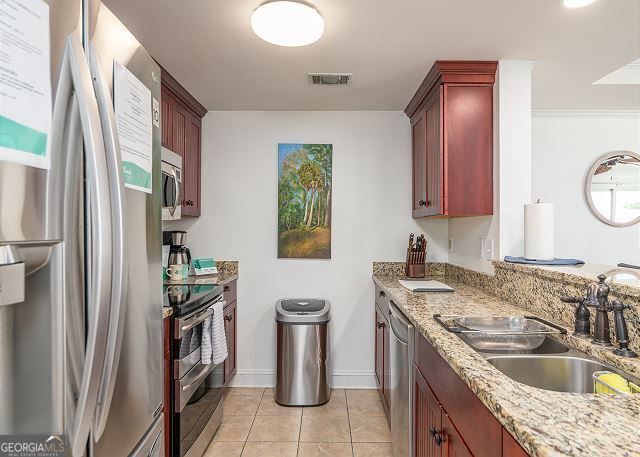 kitchen with light stone countertops, sink, light tile patterned flooring, and stainless steel appliances