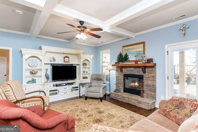 living room with coffered ceiling, ceiling fan, beamed ceiling, hardwood / wood-style floors, and a stone fireplace