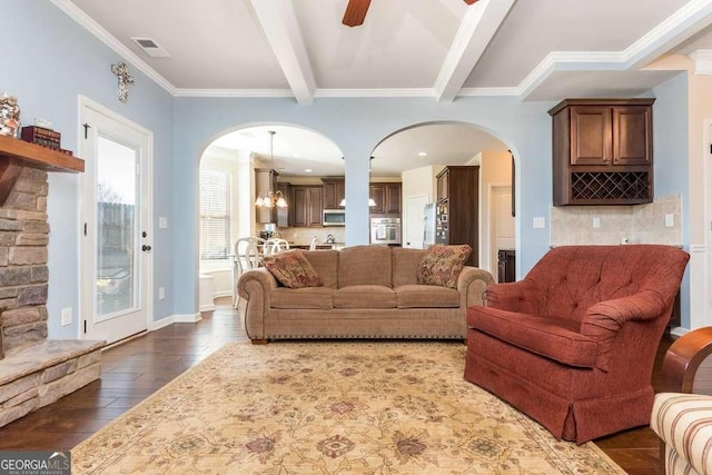 living room with ceiling fan with notable chandelier, beam ceiling, dark hardwood / wood-style flooring, and crown molding