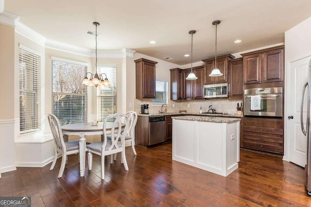 kitchen with pendant lighting, stainless steel appliances, an inviting chandelier, and a kitchen island