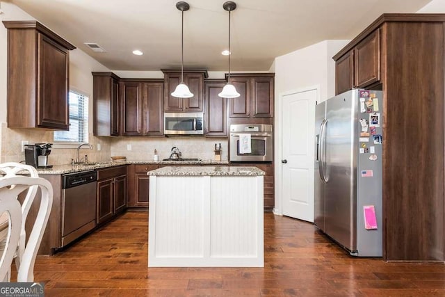 kitchen featuring decorative backsplash, appliances with stainless steel finishes, sink, pendant lighting, and a center island