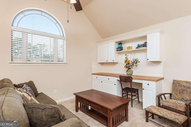 carpeted office featuring ceiling fan, high vaulted ceiling, and built in desk