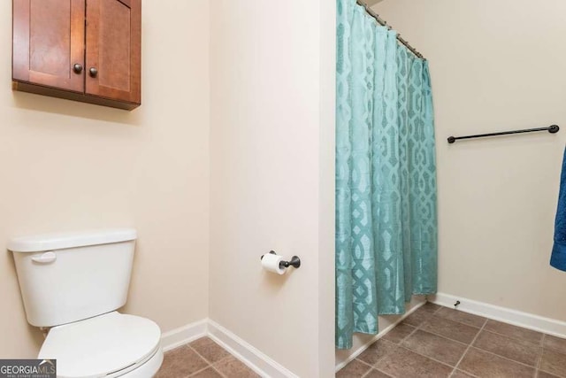 bathroom featuring tile patterned floors, curtained shower, and toilet