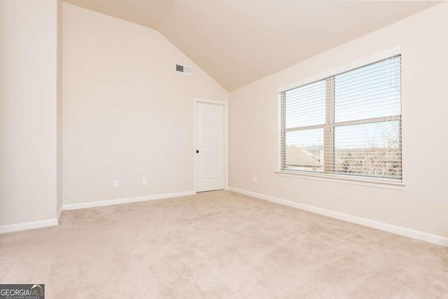 carpeted empty room featuring lofted ceiling