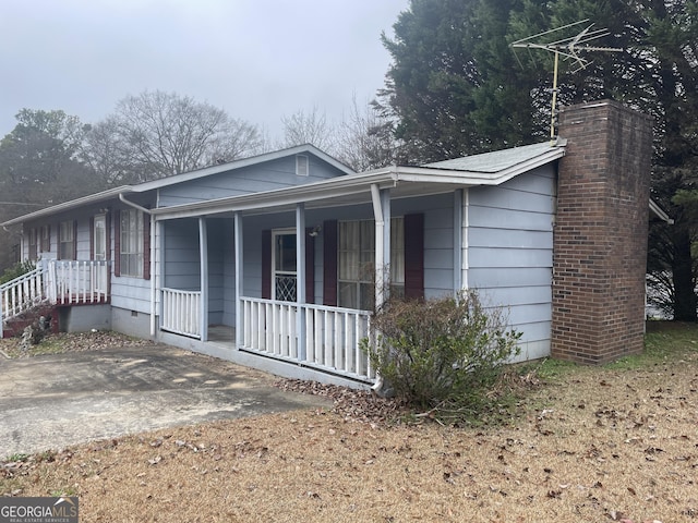 view of front of property featuring covered porch, crawl space, and a chimney