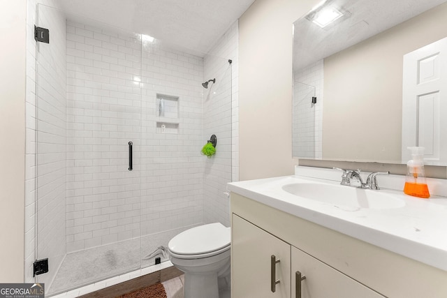 bathroom featuring a shower with door, vanity, and toilet