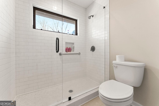 bathroom with tile patterned flooring, toilet, and a shower with door