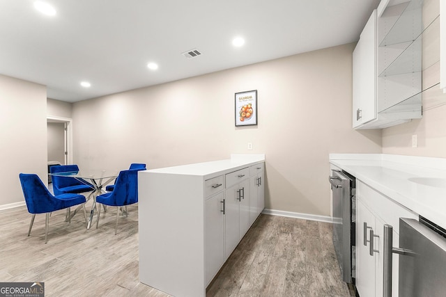 kitchen with kitchen peninsula, white cabinetry, and light hardwood / wood-style floors