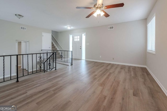 empty room featuring plenty of natural light, ceiling fan, and light hardwood / wood-style flooring