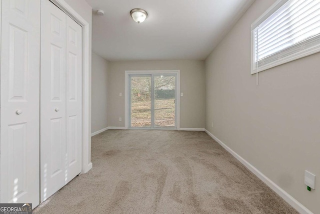 unfurnished bedroom with light carpet and a closet