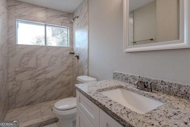 bathroom with toilet, vanity, and tiled shower