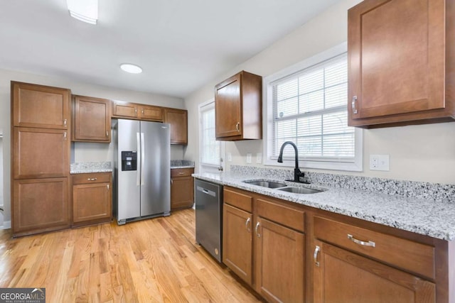 kitchen featuring sink, light stone countertops, stainless steel appliances, and light hardwood / wood-style flooring