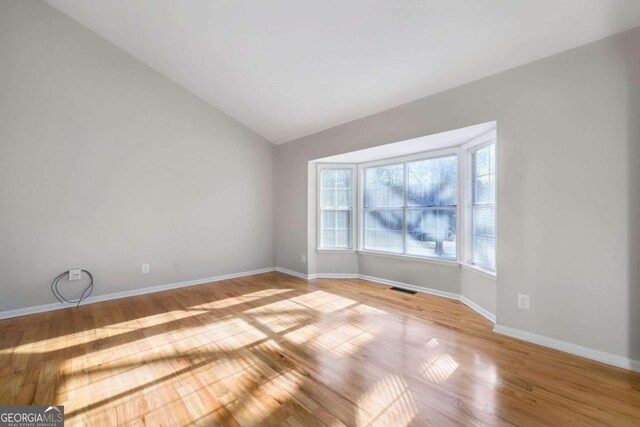 unfurnished room with light hardwood / wood-style floors and vaulted ceiling