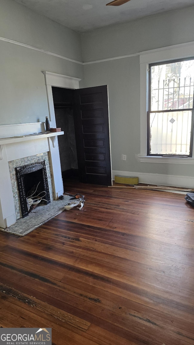 unfurnished living room featuring hardwood / wood-style flooring, ceiling fan, and a fireplace