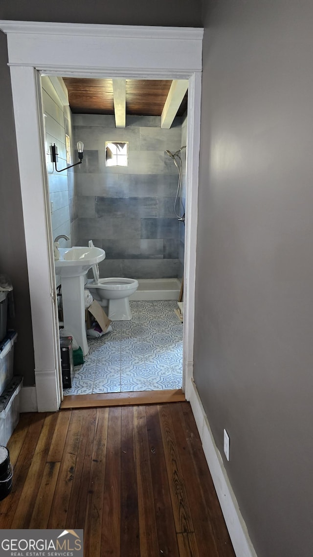 bathroom featuring hardwood / wood-style flooring, tiled shower, toilet, and sink