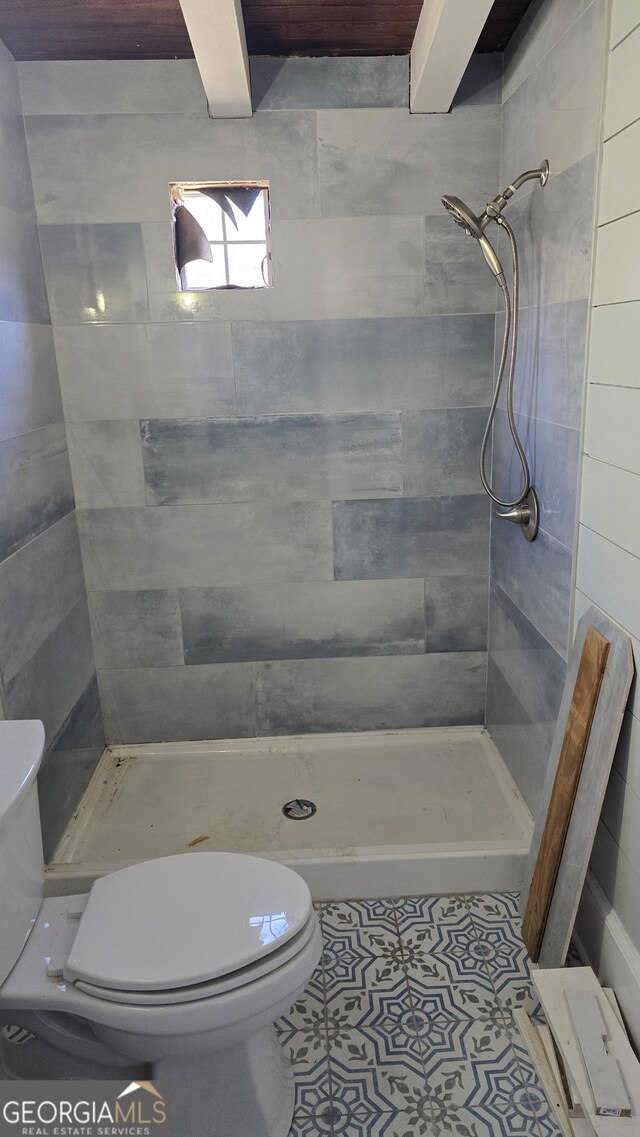 bathroom with tile patterned floors, toilet, and a tile shower