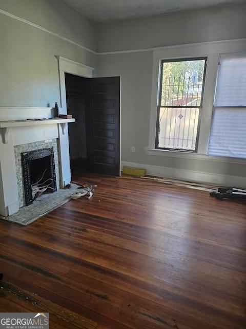 unfurnished living room featuring a high end fireplace and dark hardwood / wood-style floors