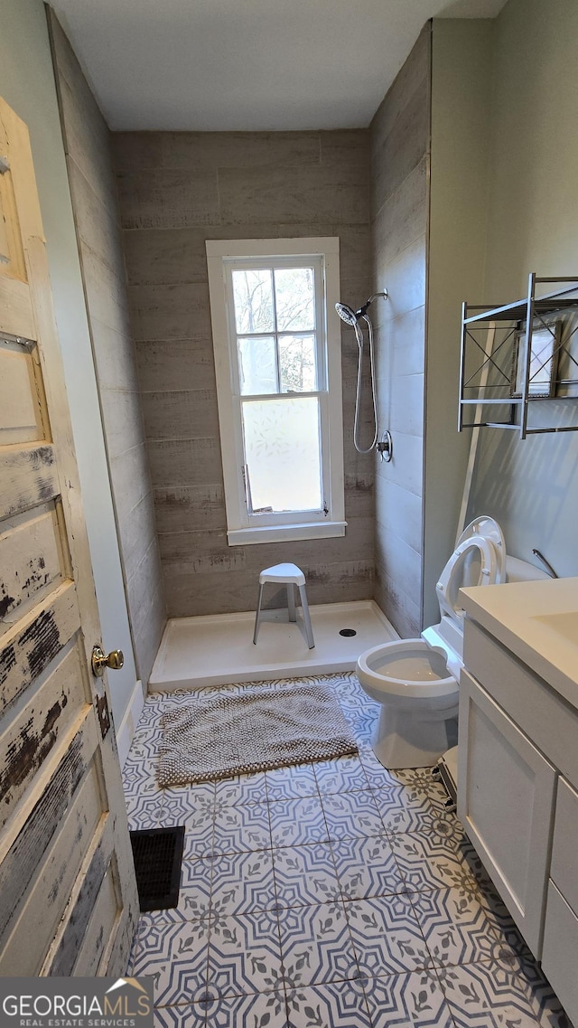 bathroom with tiled shower, vanity, toilet, and tile patterned flooring