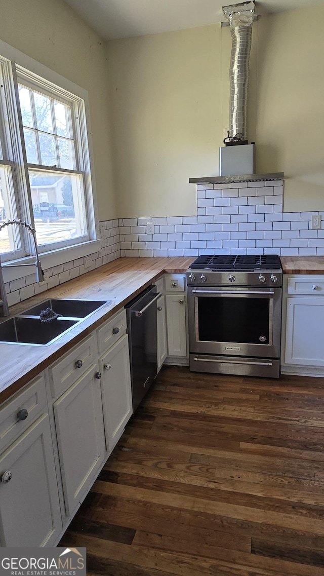 kitchen with stainless steel appliances, white cabinetry, sink, and wooden counters