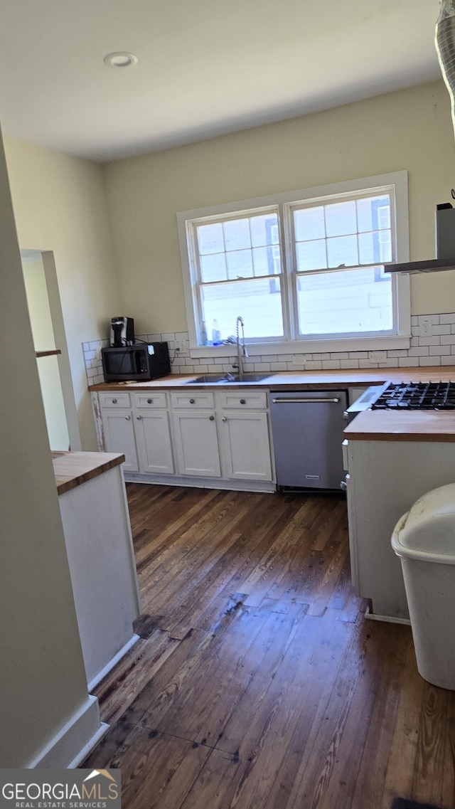 kitchen with sink, white cabinetry, stainless steel dishwasher, dark hardwood / wood-style floors, and decorative backsplash