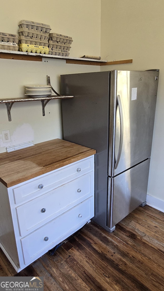 kitchen featuring dark wood-type flooring, stainless steel fridge, butcher block counters, and white cabinets