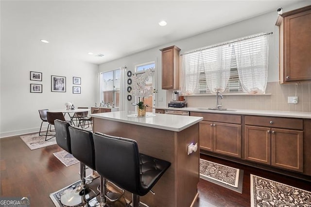 kitchen featuring decorative backsplash, dark hardwood / wood-style flooring, a breakfast bar, sink, and a kitchen island