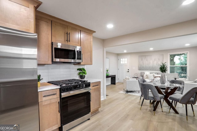 kitchen featuring stainless steel appliances, light hardwood / wood-style flooring, and tasteful backsplash