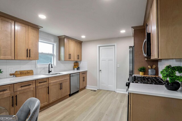 kitchen featuring light hardwood / wood-style flooring, light stone counters, sink, and stainless steel appliances