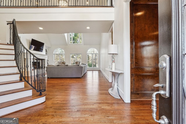 entryway with high vaulted ceiling and wood-type flooring